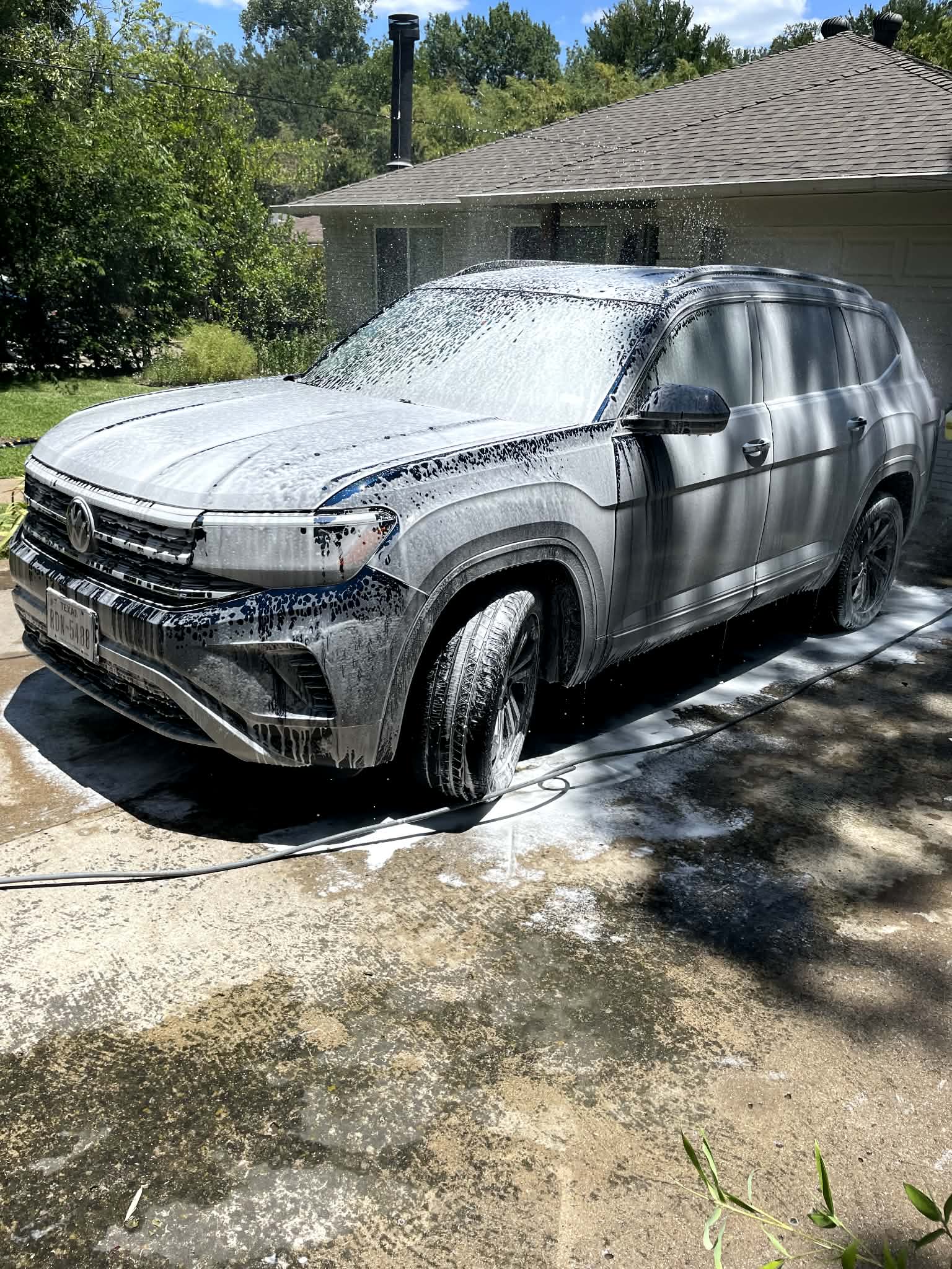 Foam pre-soak covering the front of an SUV before hand washing